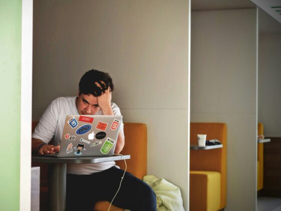 A man holding his head in frustration while working on a laptop.