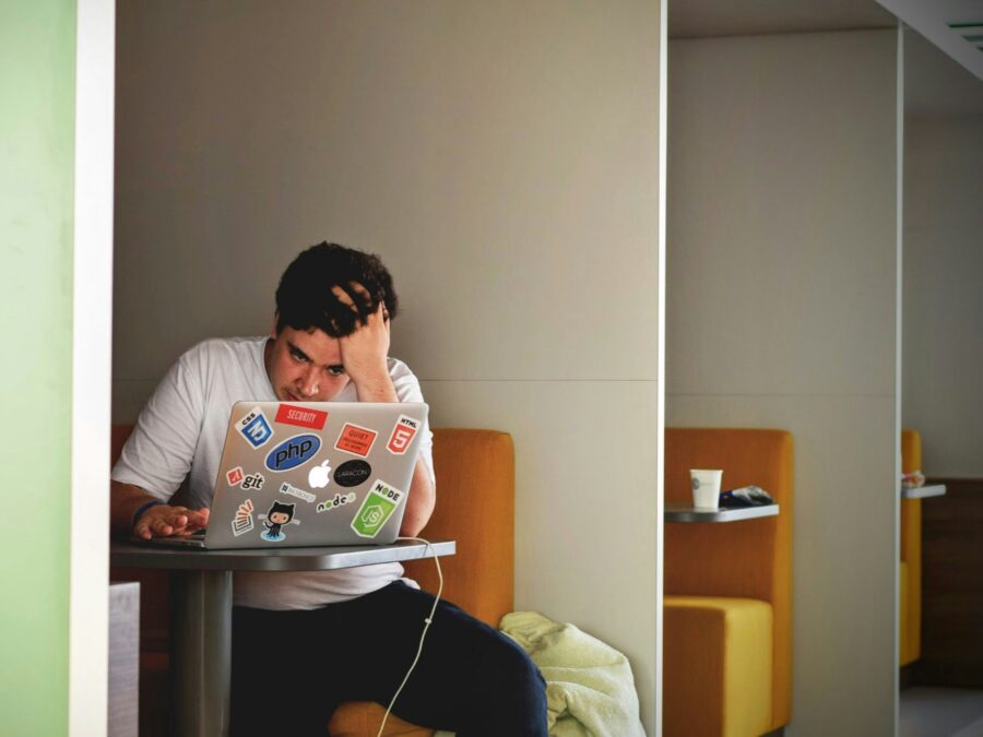 A man holding his head in frustration while working on a laptop.