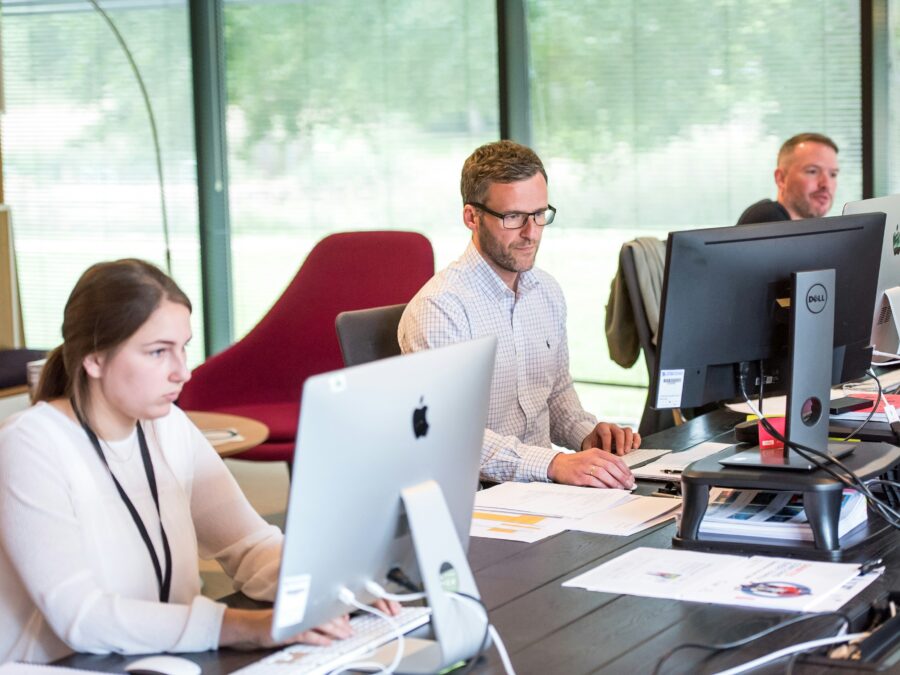 Three workers at their desks, working on computers.